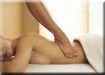 A woman's foot is shown performing barefoot shiatsu to a client's back