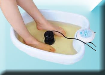 Woman's feet in a tub of water with an ionic detox system working in it.