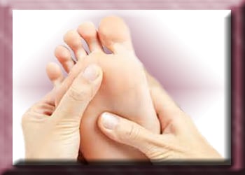 Two thumbs applying pressure to the bottom of a bare foot for Reflexology.